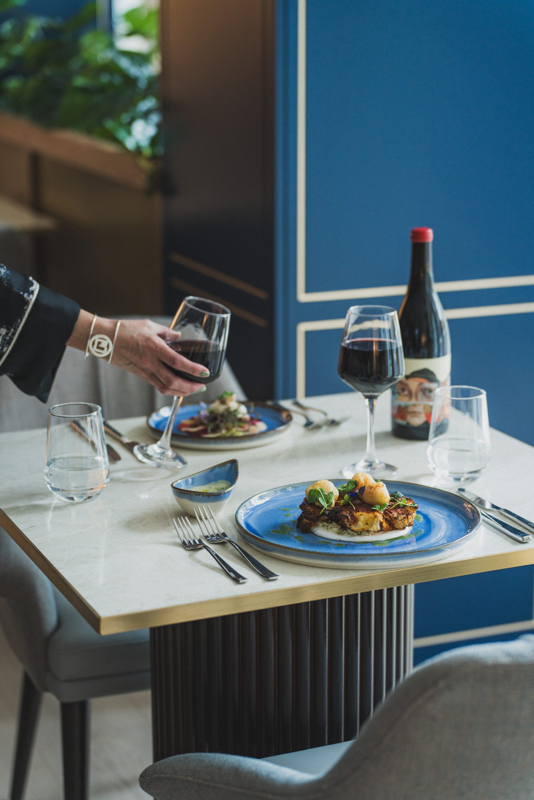 Opgemaakte finedininggerechten en rode wijn op een tafel bij Elysian Residences, een Apicbase-klant uit de hospitality